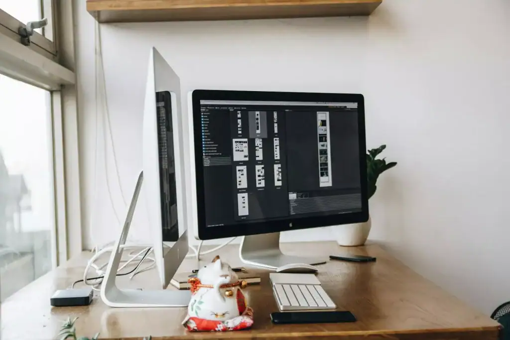 Bright, minimalist home office with computer setup and decorative cat figurine.